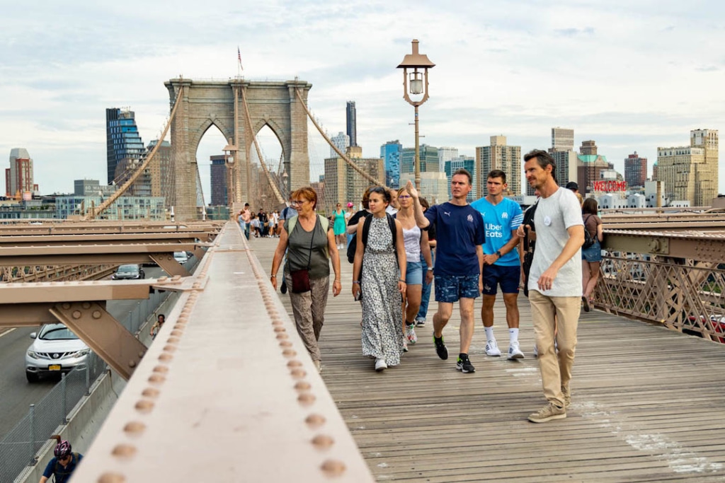 Personnes suivant une visite guidée sur le pont de Brooklyn à New York