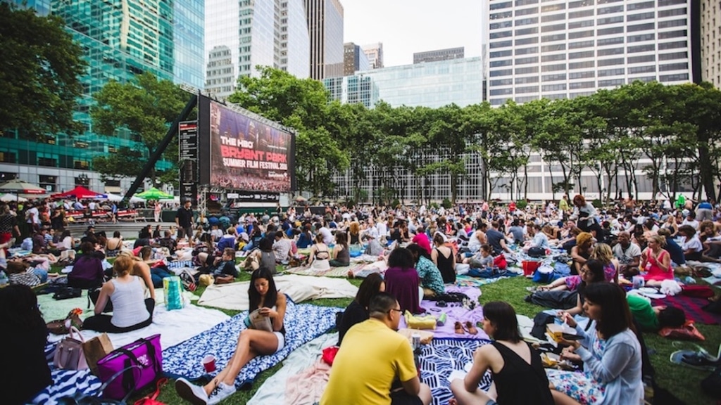 New yorkais assis sur la pelouse du Bryant Park prêt à regarder un film en plein air.