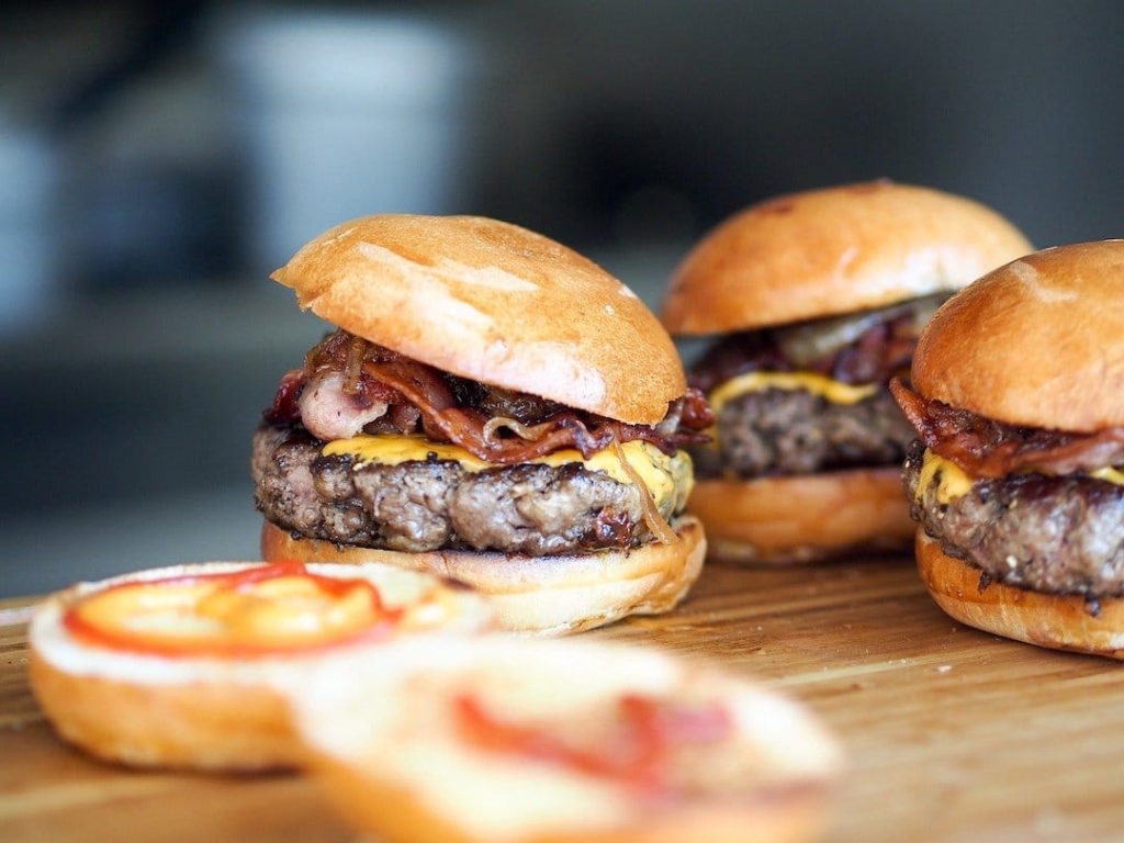 3 burgers sur une table avec des pains ouverts à l'avant