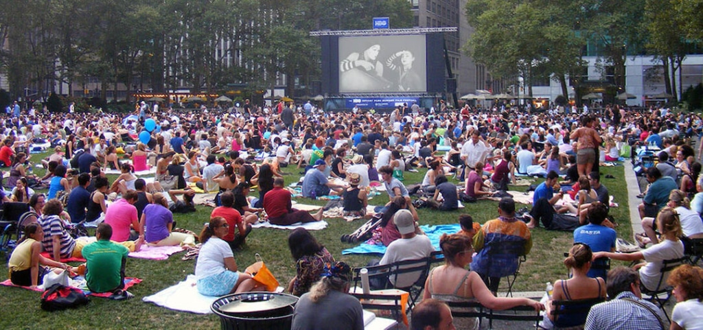 Personnes installées sur une pelouse regardant un film.