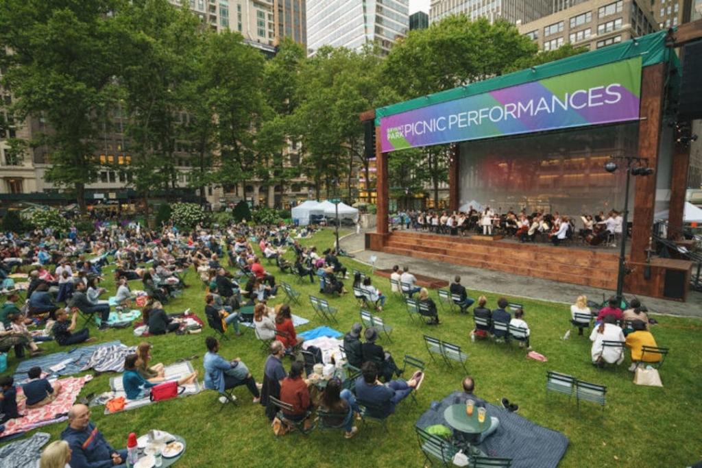 Personnes assises sur la pelouse de Bryant Park regardant un spectacle durant un Picnic Performances.