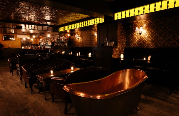 Intérieur sombre du bar BathTub Gin avec des baignoires en bronze en déco