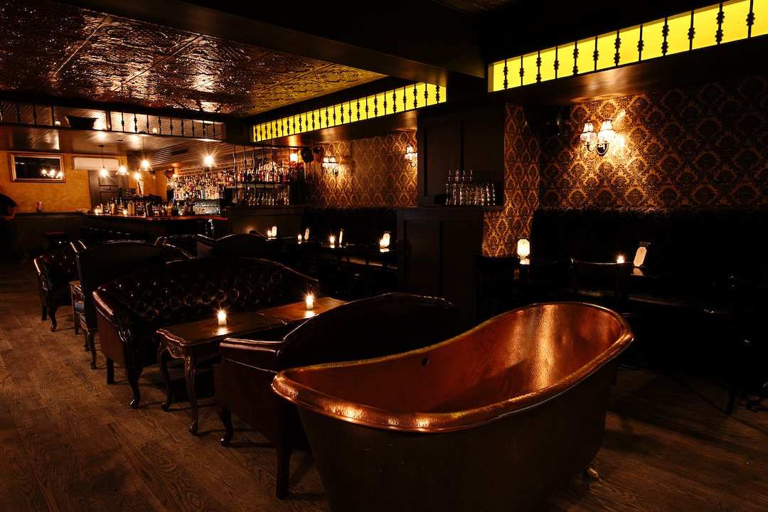 Intérieur sombre du bar BathTub Gin avec des baignoires en bronze en déco